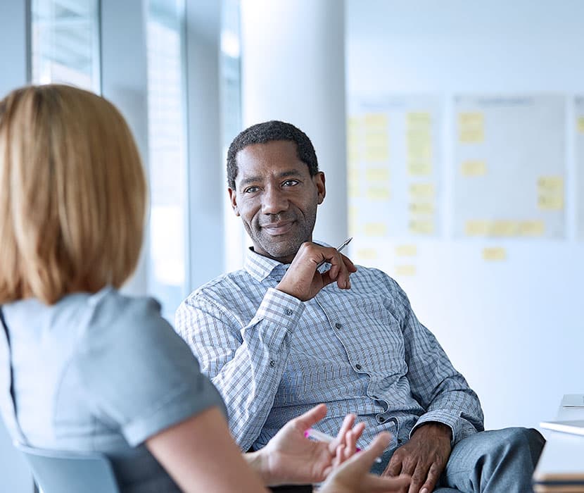 A Black male manager meeting with a co-worker.